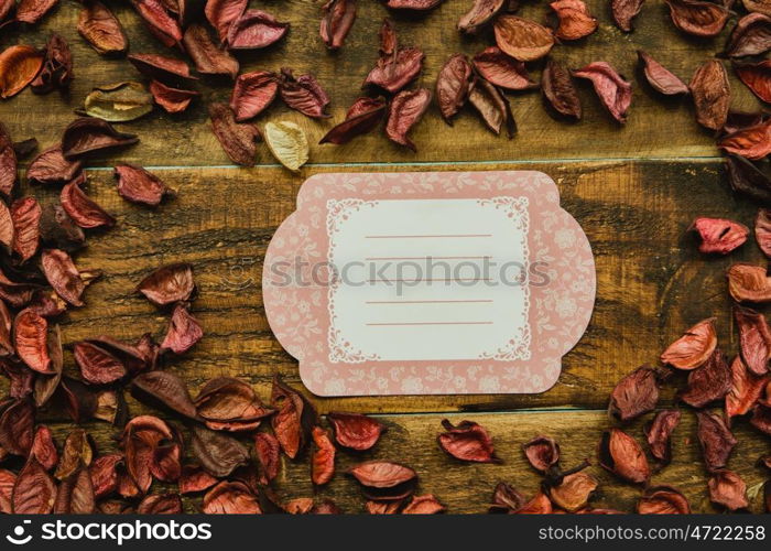 Empty shopping tag template around dry petals on a rustic wood background