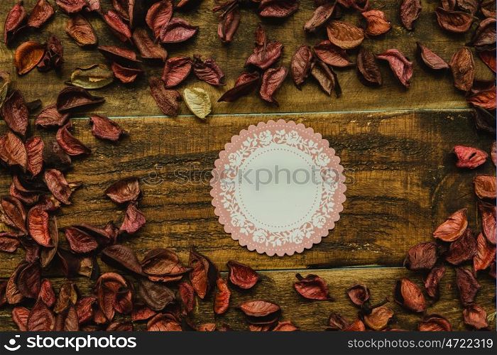 Empty shopping tag template around dry petals on a rustic wood background