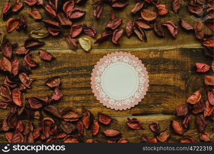 Empty shopping tag template around dry petals on a rustic wood background