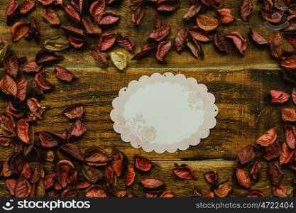 Empty shopping tag template around dry petals on a rustic wood background