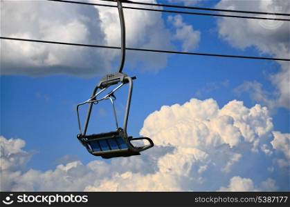 Empty ski lift chair above clouds and sky
