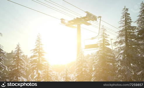 empty ski lift. chairlift silhouette on high mountain over the forest at sunset