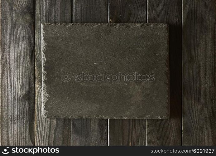 Empty slate plate over black wooden background