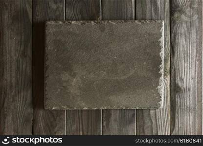 Empty slate plate over black wooden background