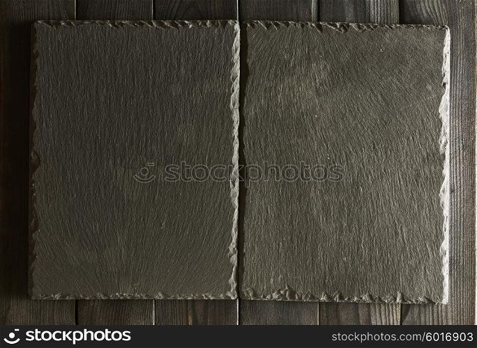Empty slate plates over black wooden background