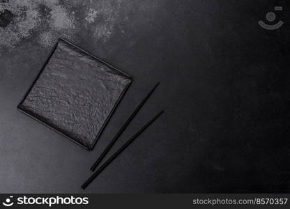 Empty square black plate over dark slate. Aerial view, with copy space. Empty square black plate on dark moody background with copy space