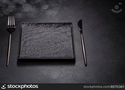 Empty square black plate over dark slate. Aerial view, with copy space. Empty square black plate on dark moody background with copy space