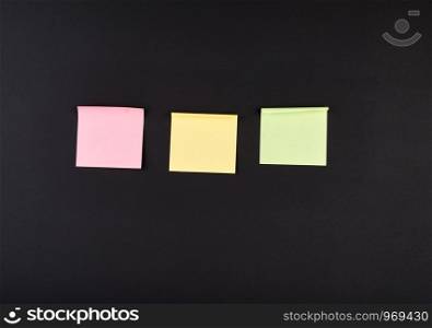 empty square multi-colored stickers hang on a black board in a wooden frame, business concept