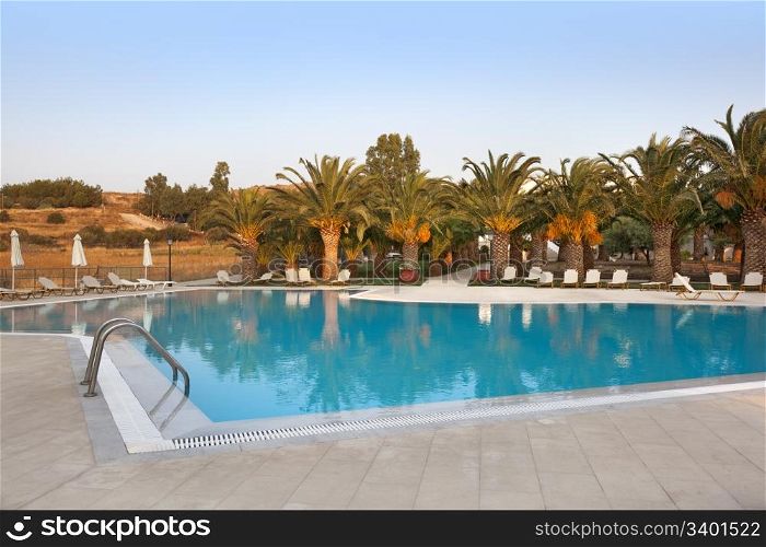Empty swimmingpool with palmtrees at sundown