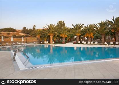 Empty swimmingpool with palmtrees at sundown