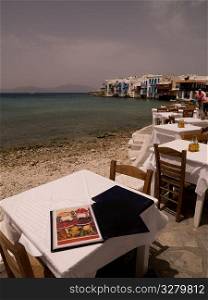 Empty table and chairs by seashore in Mykonos Greece