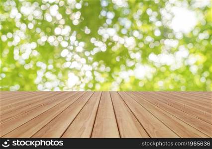 Empty table board with blurry bokeh of abstract nature green tree in forest or park with sunlight flare. Pattern texture background in spring season in ecology, holiday vacation and travel concept.