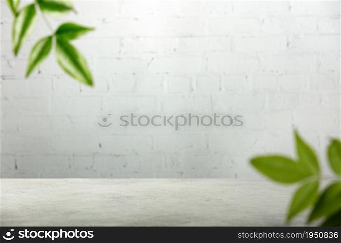 Empty table top, green leaves and white brick wal, Suitable for Product Presentation Backdrop, Display, and Mock up.