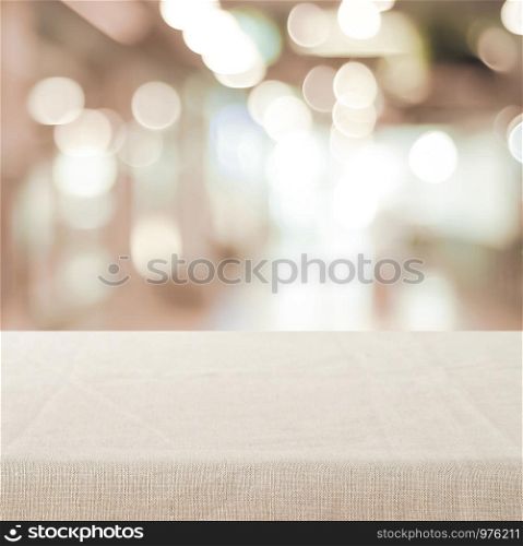 Empty table with linen tablecloth over blurred store with bokeh background banner, product display montage