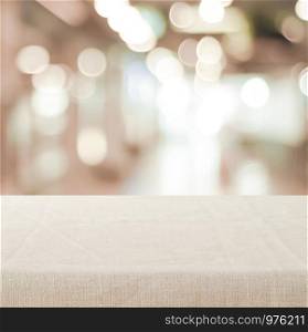 Empty table with linen tablecloth over blurred store with bokeh background banner, product display montage
