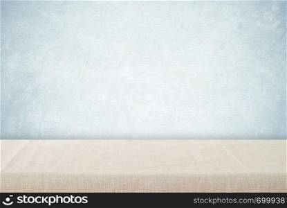 Empty table with linen tablecloth over vintage cement wall background, product display montage