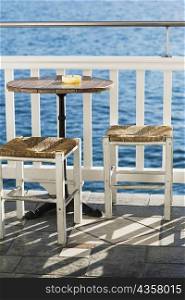 Empty table with stools near a railing in a restaurant, Mykonos, Cyclades Islands, Greece