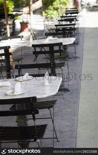 Empty tables and chairs at a sidewalk cafe
