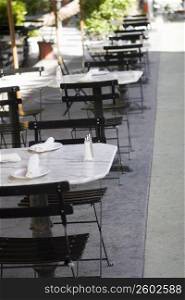 Empty tables and chairs at a sidewalk cafe