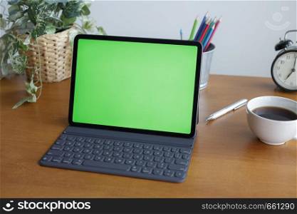 Empty tablet has a green screen on the desk
