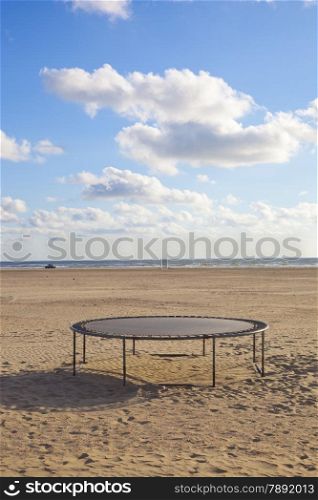 Empty trampoline at beach with blue sky