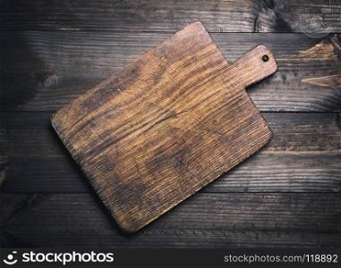 empty very old brown wooden kitchen cutting board with a handle on the table, top view. empty very old brown wooden kitchen cutting board