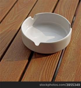 empty white ashtray on a wooden table