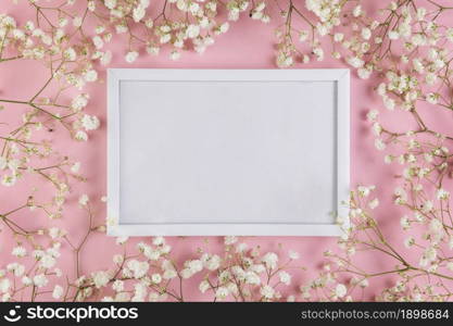 empty white blank frame surrounded with white baby s breath flowers against pink background. Resolution and high quality beautiful photo. empty white blank frame surrounded with white baby s breath flowers against pink background. High quality beautiful photo concept