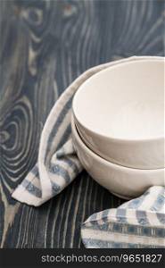 Empty white bowls wrapped with napkin on blue wooden background with copy space