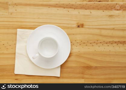 empty white china coffee cup and napkin on pine wood table, top view