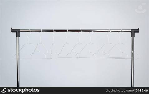 empty white metal hangers hang on a chrome bar, white background, close up