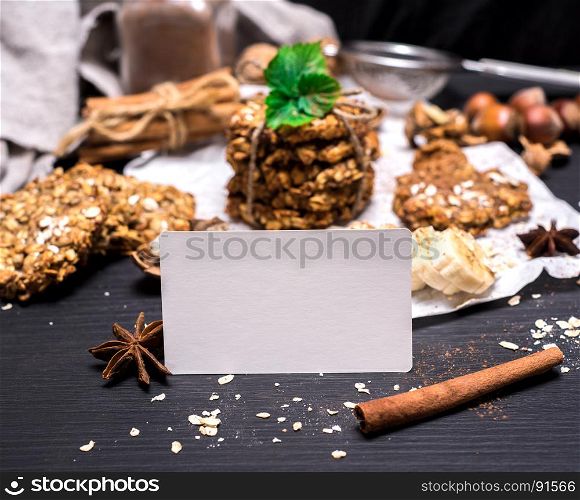 empty white paper tag on a black wooden table and oatmeal cookies and ingredients
