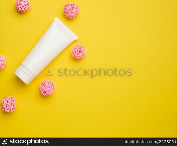 empty white plastic tubes for cosmetics on a yellow background. Packaging for cream, gel, serum, advertising and product promotion, top view
