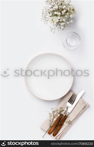 Empty white plate and cutlery on a napkin, flat lay on white background . Empty white plate and cutlery on a napkin
