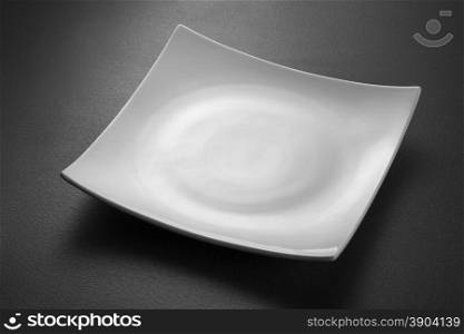Empty white plate on black textured background. Empty white plate on black background