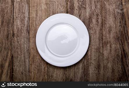 Empty white plate on wooden table background