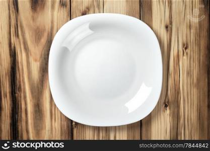 Empty white plate on wooden table background. Top view