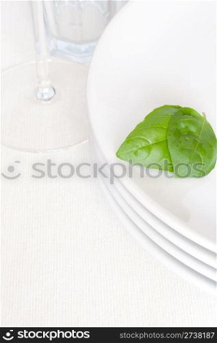 Empty White Plates With Basil Leaf and Wine Glass on Light Tablecloth