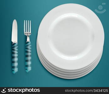 empty white plates with knife and fork on blue background.