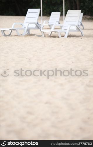 empty white pool plastic chairs deckchairs on sand beach. Vacation concept