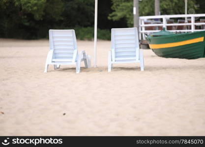 empty white pool plastic chairs deckchairs on sand beach. Vacation concept