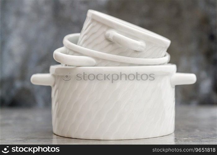 Empty white porcelain saucepans without covers on gray background