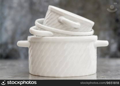 Empty white porcelain saucepans without covers on gray background