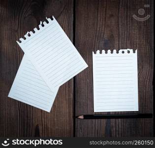 empty white sheets in a line torn out of notepad on a brown wooden background