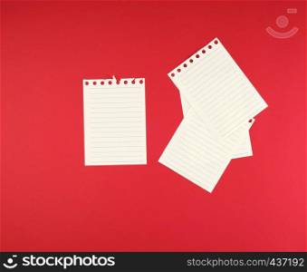 empty white sheets in a line torn out of notepad on a red background