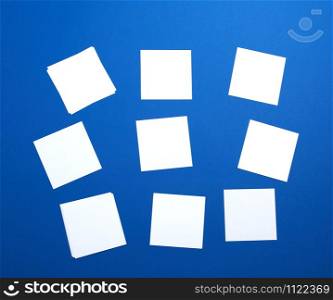 empty white small square sheets of paper on a blue background. Mockup template. Business background.