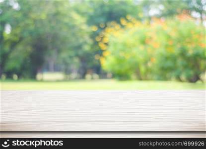 Empty white wood table over blur green park nature background, tabletop, shelf, counter for product display montage