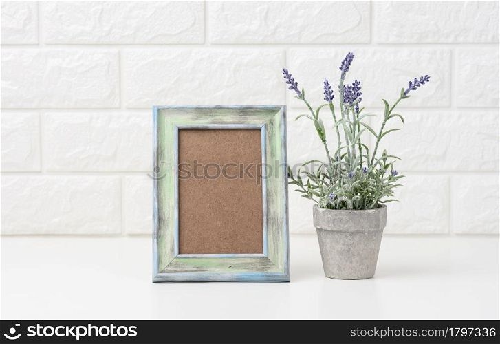 empty white wooden photo frame and flowerpots with plants on white table, white background