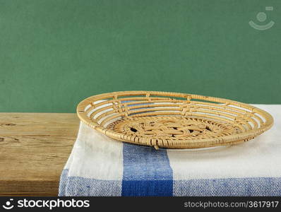 empty wicker basket on an old wooden table against grunge wall