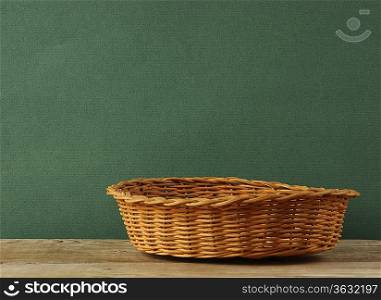 empty wicker basket on an old wooden table against grunge wall